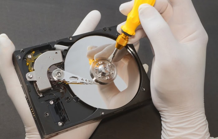 Technician using screwdriver on open hard drive platter