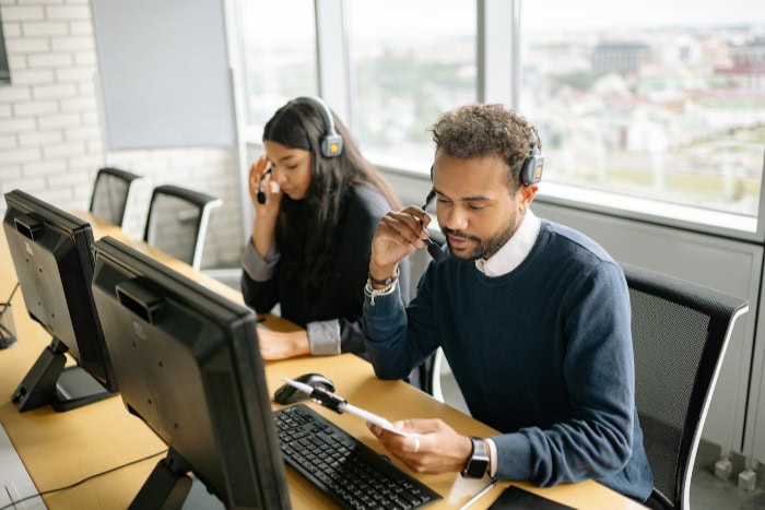 Telemarketer working at computers with headsets