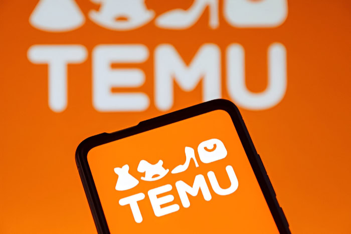 Temu logo displayed on smartphone with orange background