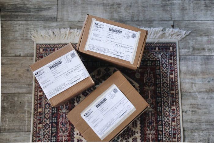 Three cardboard shipping boxes with labels on rug