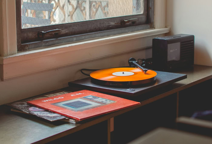 Turntable playing orange vinyl record near Wilco album