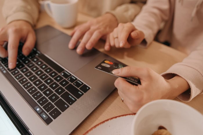 Two people entering credit card information on a laptop