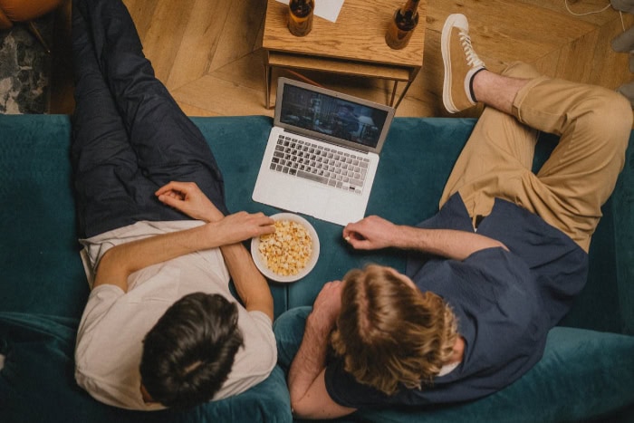 Two people watching a movie on a laptop with popcorn