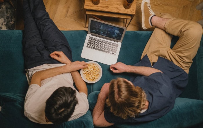 Two people watching movie on laptop with popcorn