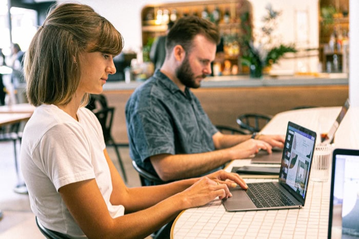 Two people working on laptops in a cafe