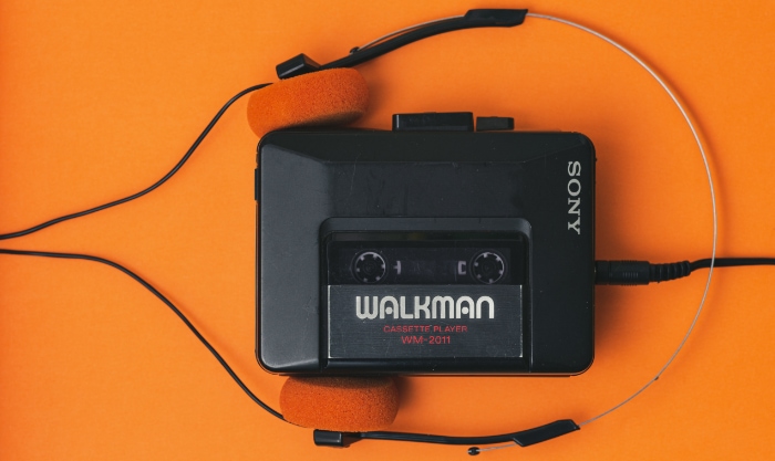 Black walkman with headphone on orange surface