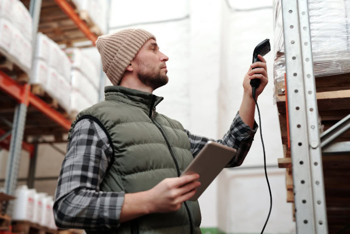 Warehouse worker scanning pallet with handheld barcode scanner