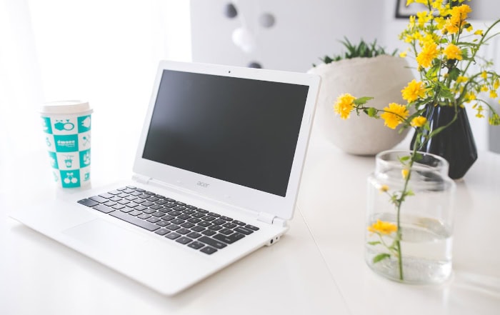 White Acer laptop on desk with yellow flowers