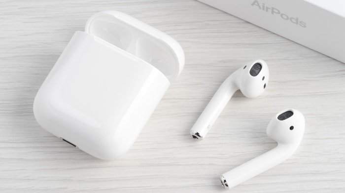 White AirPods and case with original packaging on a wooden surface