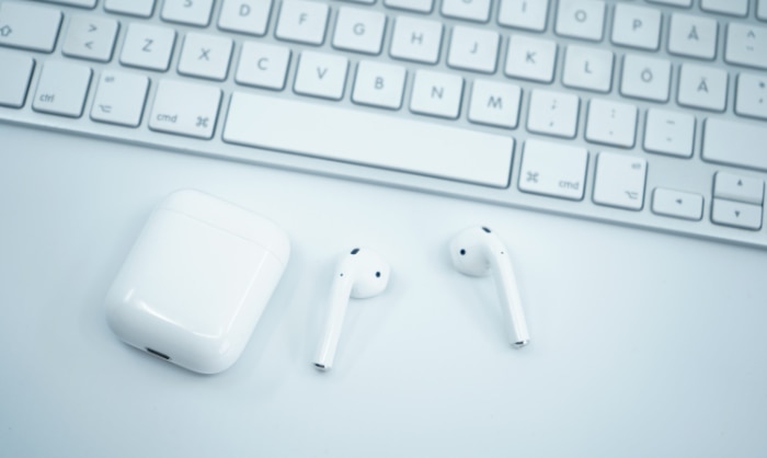 White AirPods and charging case on a white keyboard
