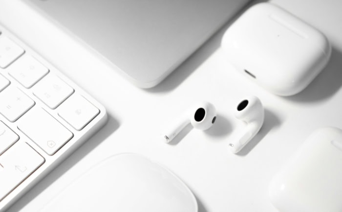 White Airpods and mouse on minimalist white desk