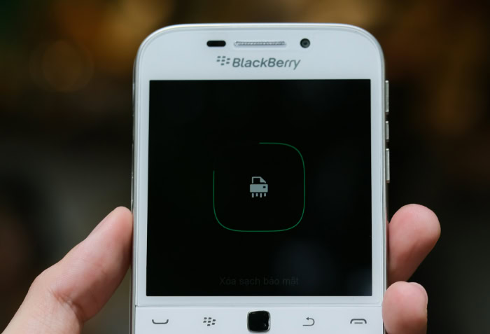 White BlackBerry phone with physical keyboard in hand