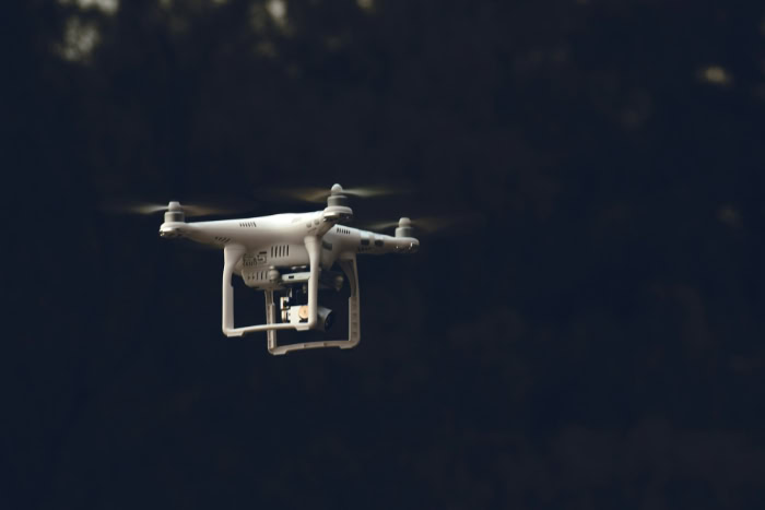 White DJI Phantom drone flying against dark background