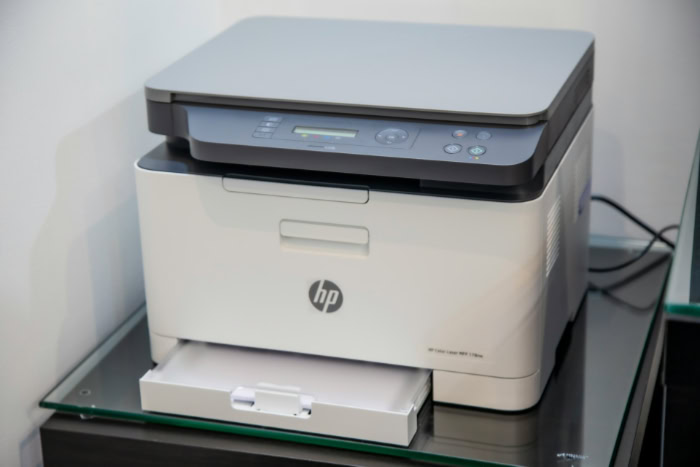 White HP multifunction laser printer on glass table