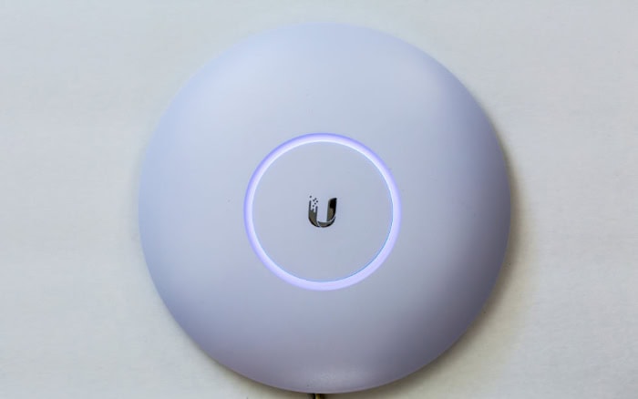 White Ubiquiti wireless access point with glowing blue ring
