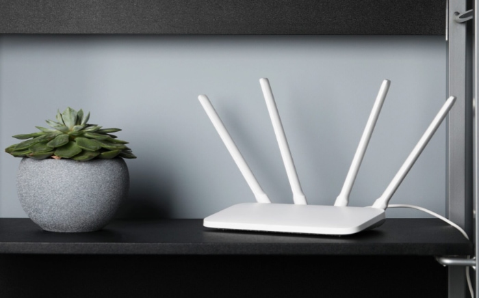White Wi Fi router with four antennas next to a potted succulent