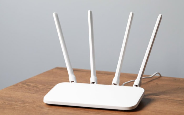 White WiFi router with four antennas on wooden surface