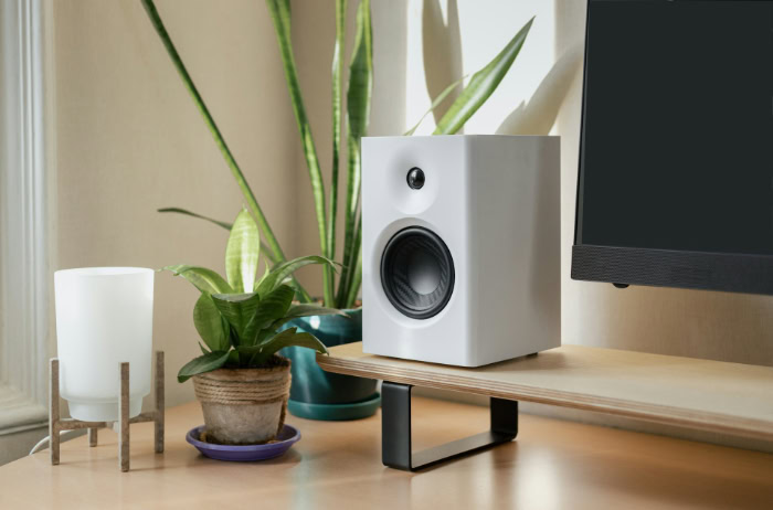 White bookshelf speaker on a wooden desk shelf