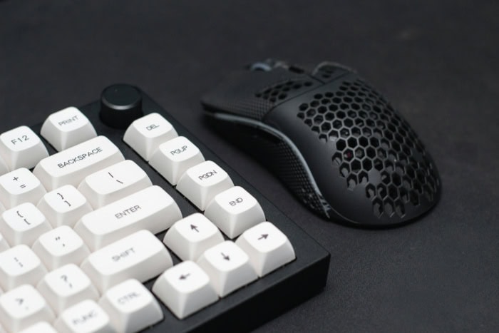 White mechanical keyboard next to a lightweight honeycomb mouse