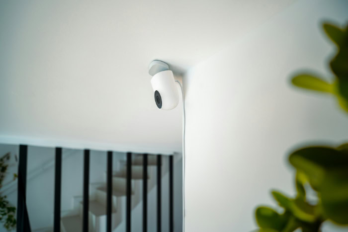 White security camera mounted near an indoor staircase