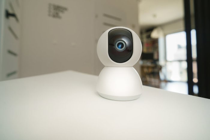 White smart security camera on desk in home setting