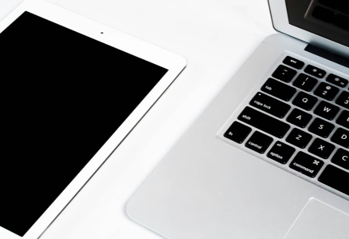 White tablet beside laptop keyboard