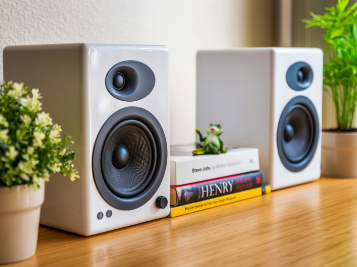 White wired bookshelf speakers on a wood table