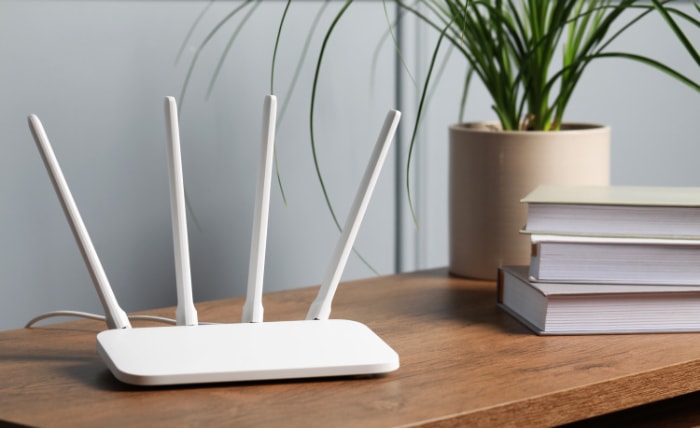 WiFi router on a wooden desk with books and a potted plant