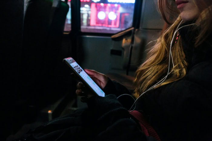 Woman browsing her phone on a bus at night