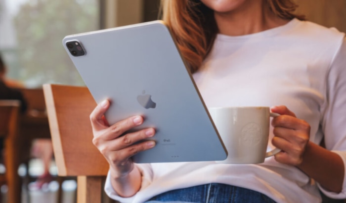 Woman holding an iPad and coffee cup in a cafe