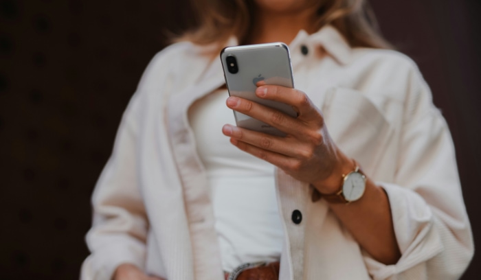 Woman holding an iPhone in white clothes