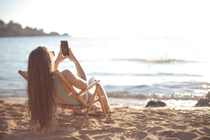 Woman holding iphone at the beach