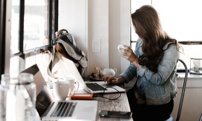 Woman holding tea cup and using laptop