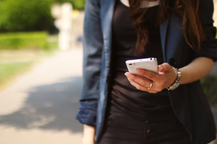 Woman in black jacket using smartphone outdoors