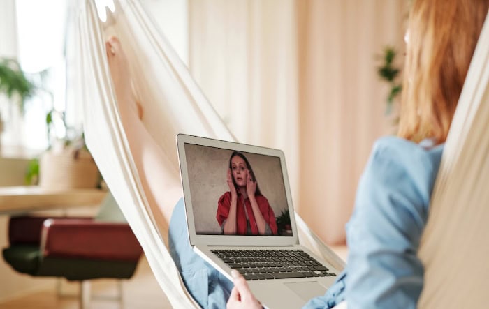 Woman in hammock using laptop for video streaming