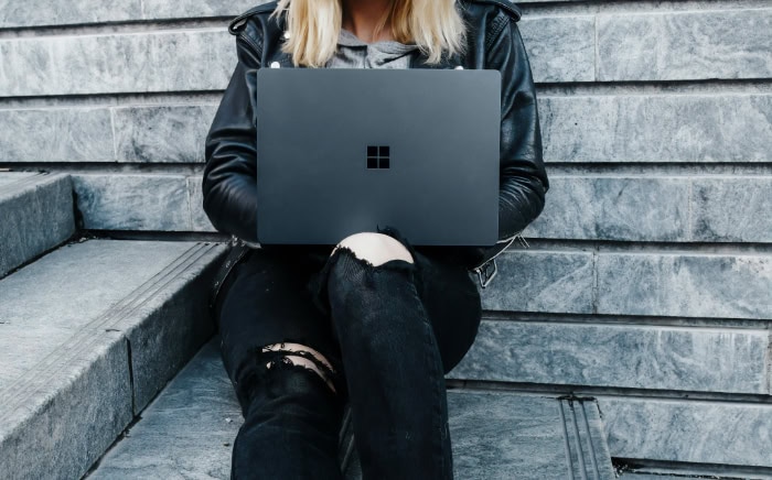 Woman in leather jacket using laptop on steps