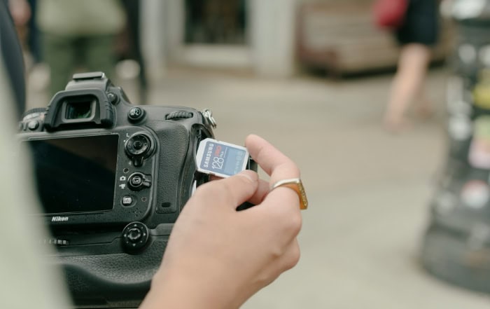 Woman inserting memory card into Nikon DSLR camera