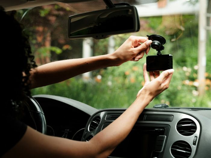 Woman installing dashcam on car windshield