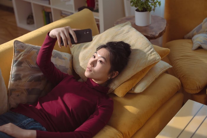 Woman lying on couch taking a selfie