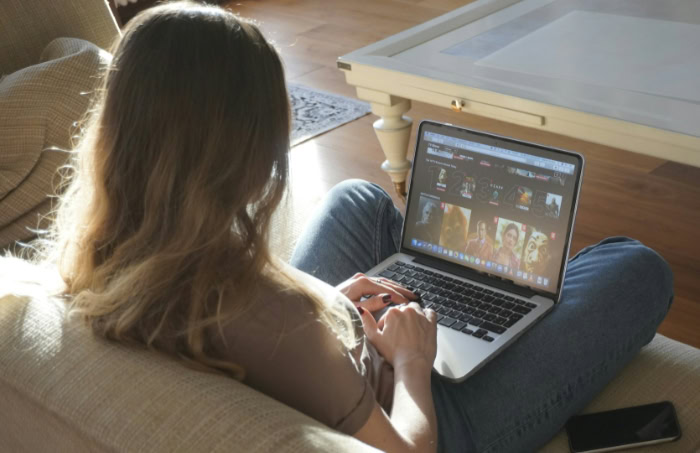 Woman on couch streaming shows on laptop