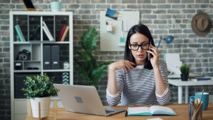 Woman on phone call while working at laptop