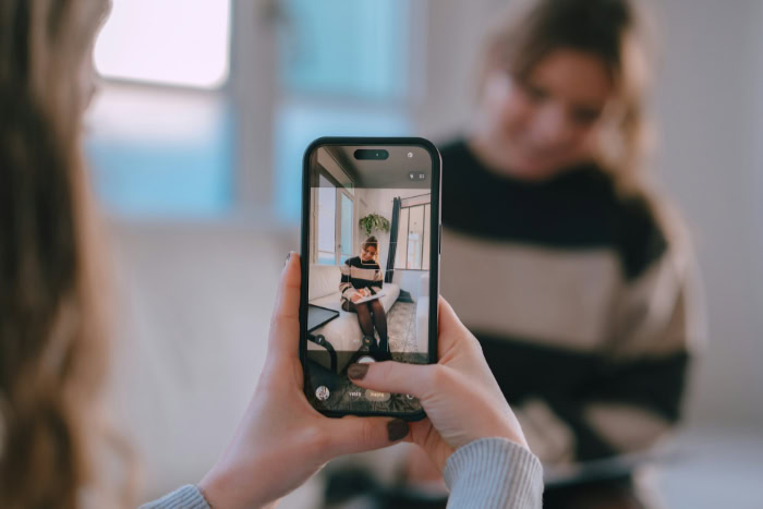 Woman photographing another woman with smartphone