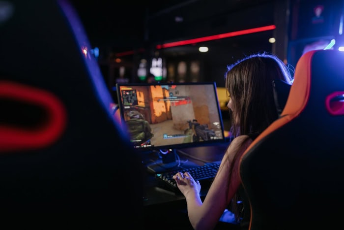 Woman playing first person shooter game on gaming PC setup