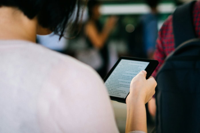 Woman reading a Kindle while commuting in public