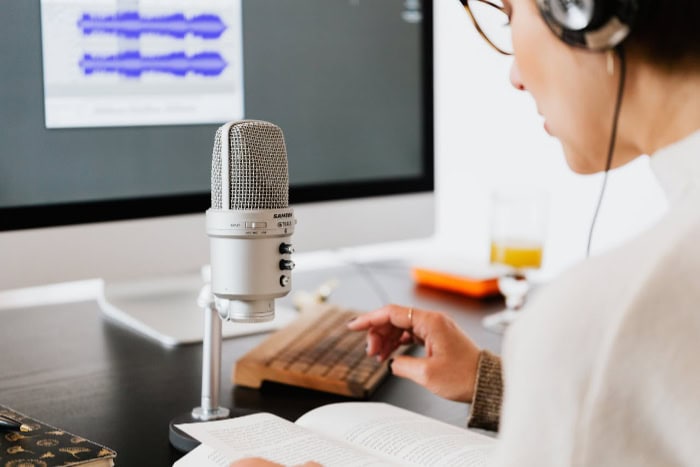 Woman recording audio with microphone and headphones