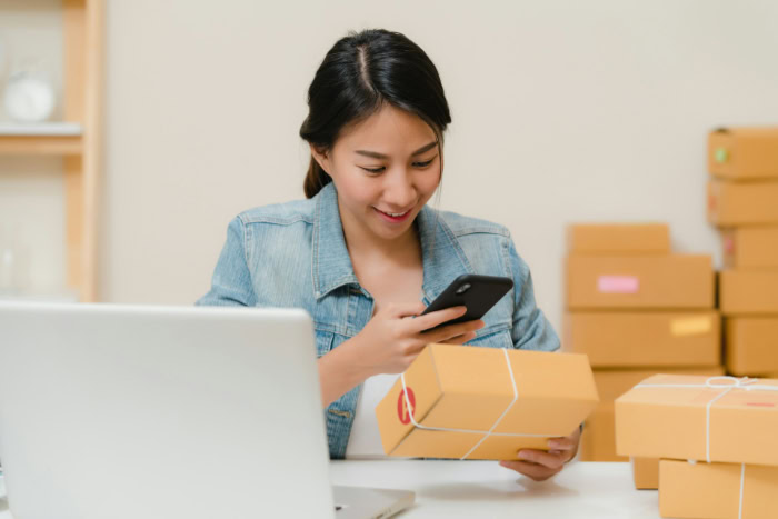 Woman scanning shipping package with her smartphone