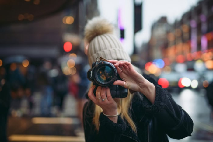 Woman taking photo with Canon camera in city street