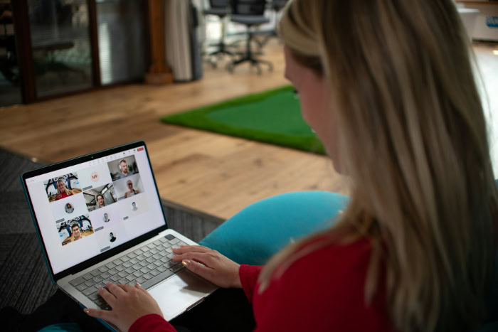 Woman typing on laptop during virtual team meeting