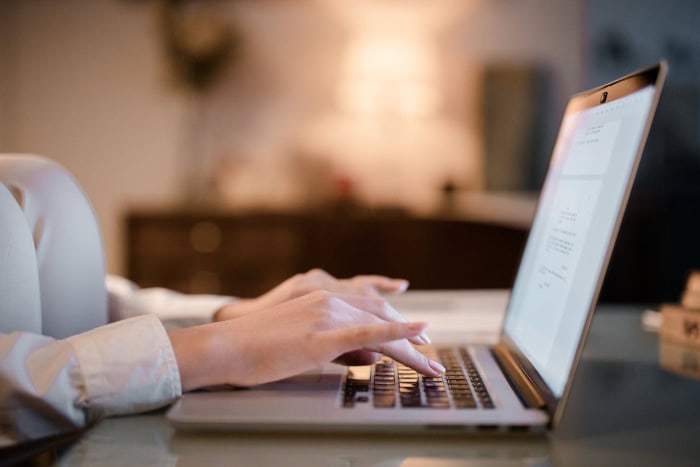 Woman typing on laptop keyboard in dimly lit room