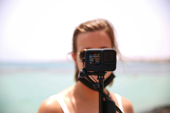 Woman using GoPro on selfie stick at beach